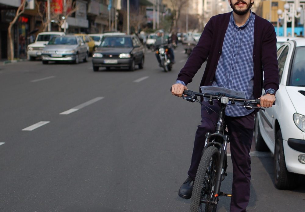 Bicycle Mayor of Tehran on his bike, with a busy street behind him